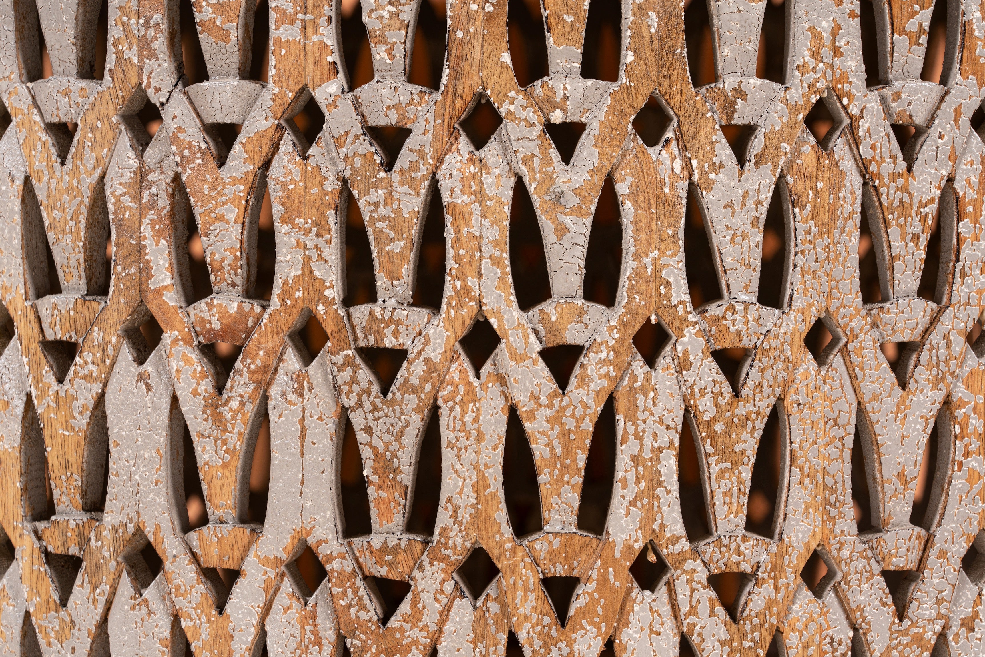 Close up image of a round hand carved mango wood coffee table with white-washed base and natural wood top; 90 cm diameter, 45 cm height.
