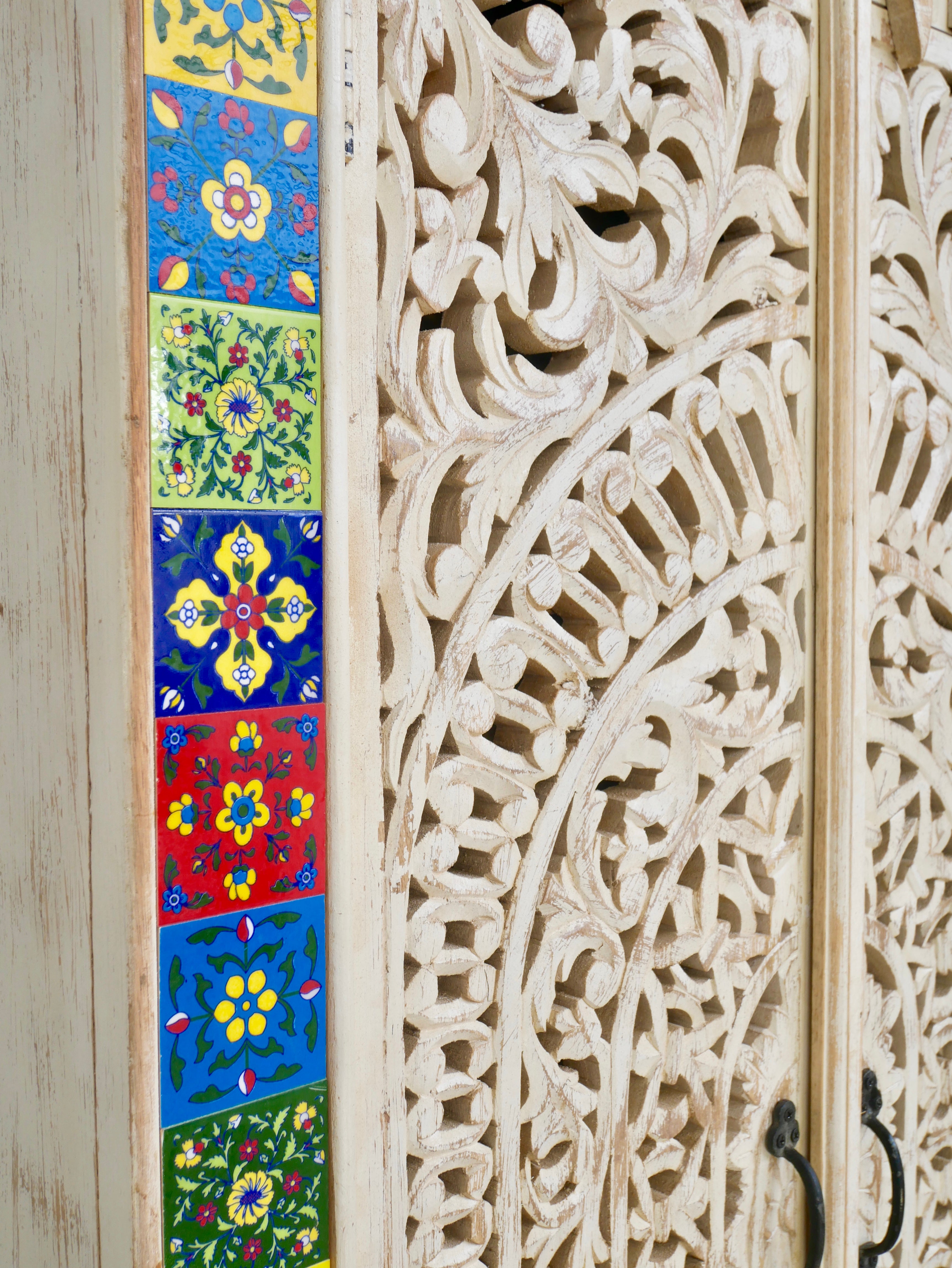 Close up image of a hand-carved mango wood cabinet with white-wash finish and ceramic detailing – artisanal furniture and carved wooden furniture with Mediterranean flair.