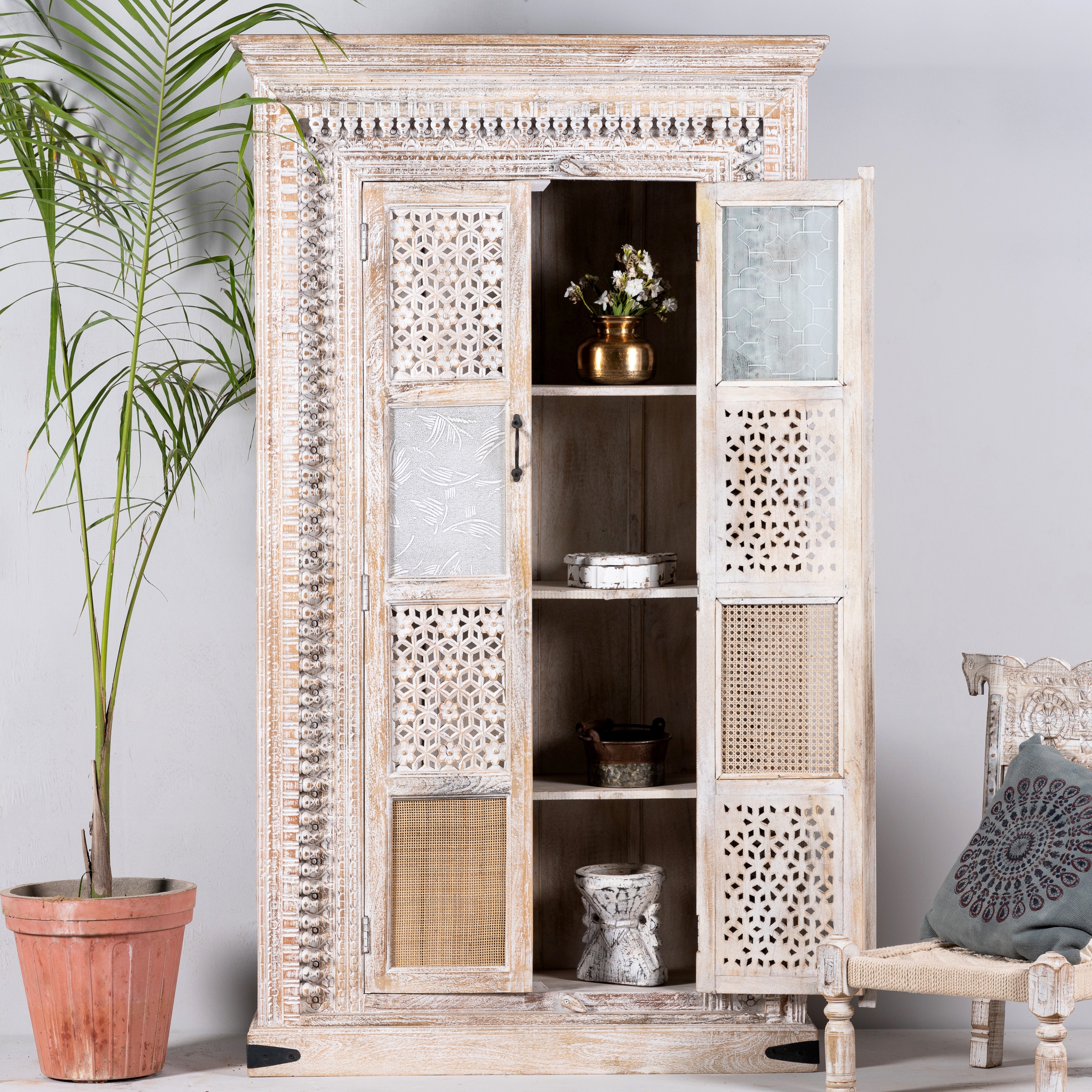 Open door image of a whitewashed mango wood cabinet with hand-carved details, rattan inserts, and glass panels; versatile as bedroom furniture or wooden wardrobe; 192 × 110 × 40 cm.