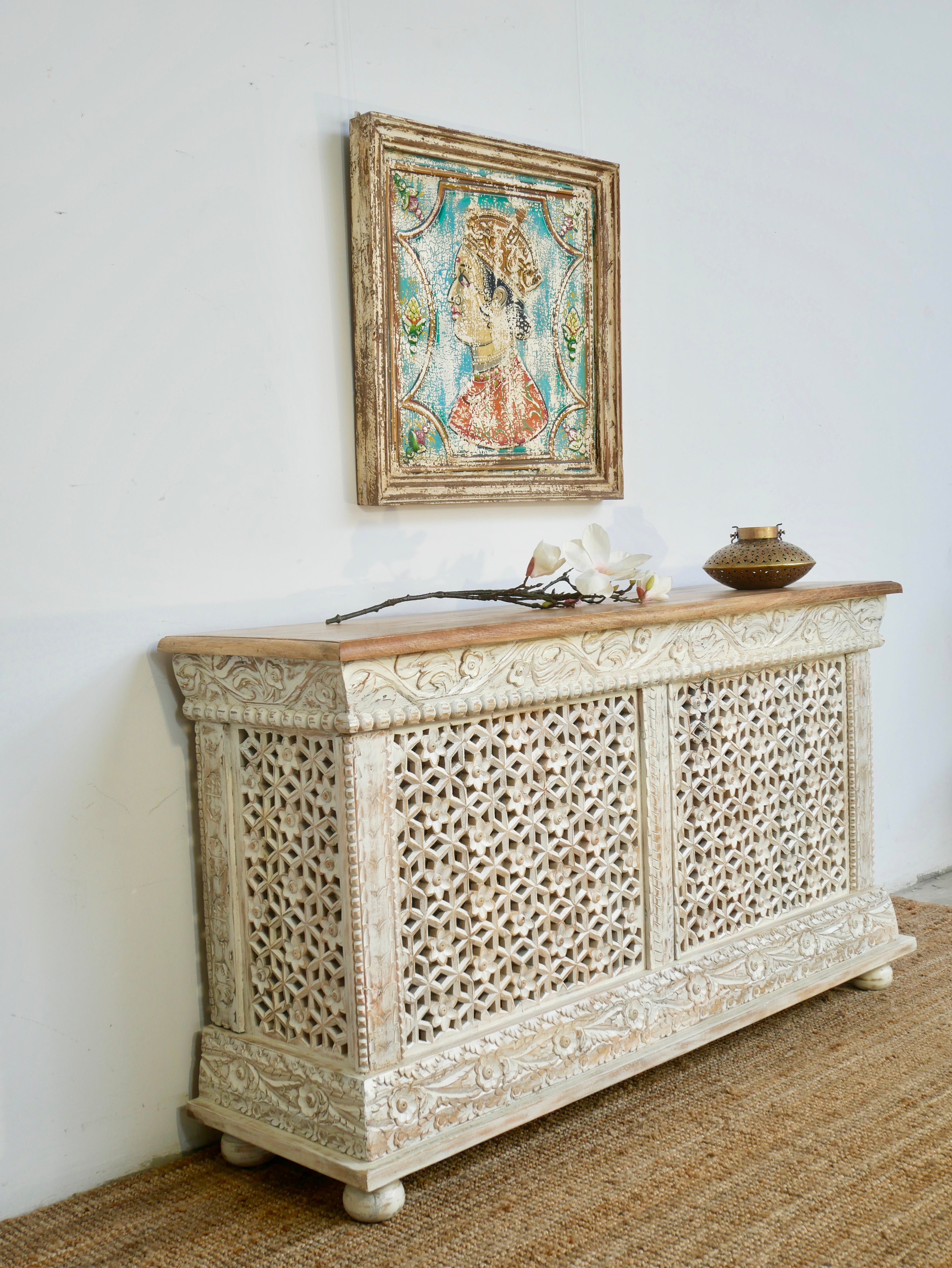 Side angle image of a handcrafted mango wood carved console table with Indian motifs; vintage-style entryway table with storage shelf, 150 × 90 × 40 cm.