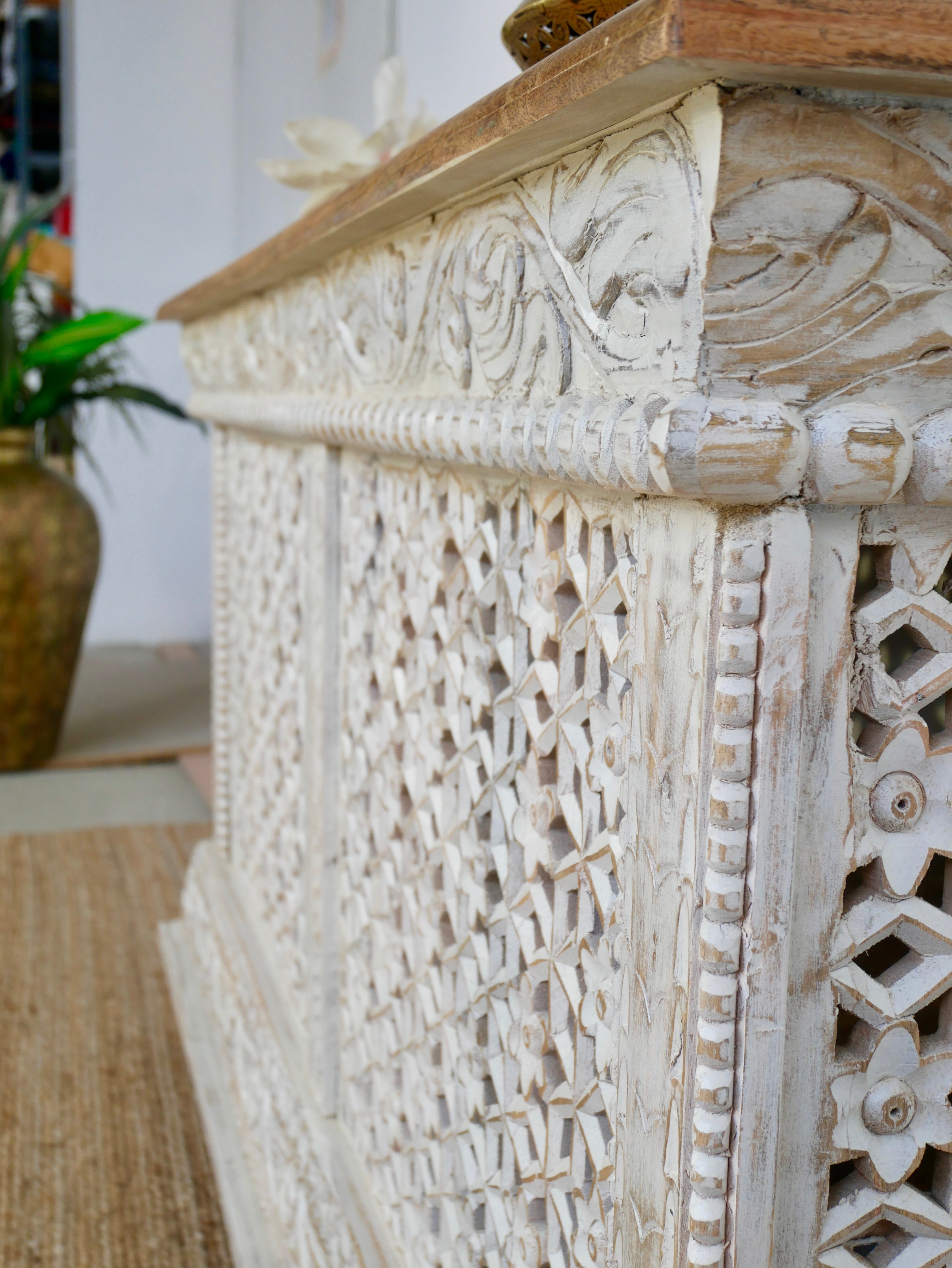 Close up image of a handcrafted mango wood carved console table with Indian motifs; vintage-style entryway table with storage shelf, 150 × 90 × 40 cm.
