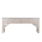 White background image of a handcarved console table made from reclaimed wood, showcasing an ornate floral design with a whitewashed finish that highlights the intricate details and natural imperfections of the repurposed material.
