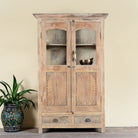 Reclaimed teak wood showcase Aasta with Mediterranean design, featuring hand-carved doors, glass panels, and drawers. A unique piece of refurbished Indian furniture offering elegant display and practical storage.