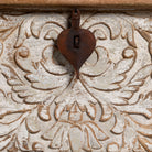 Close up image of a hand-carved mango wood chest box with floral whitewashed detailing and iron handles – vintage home accessory and unique furniture with rustic charm.