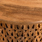 Close up image of a round mango wood coffee table with hand-carved lattice base and smooth natural top; carved coffee table mango wood, 90 cm diameter, 45 cm height.