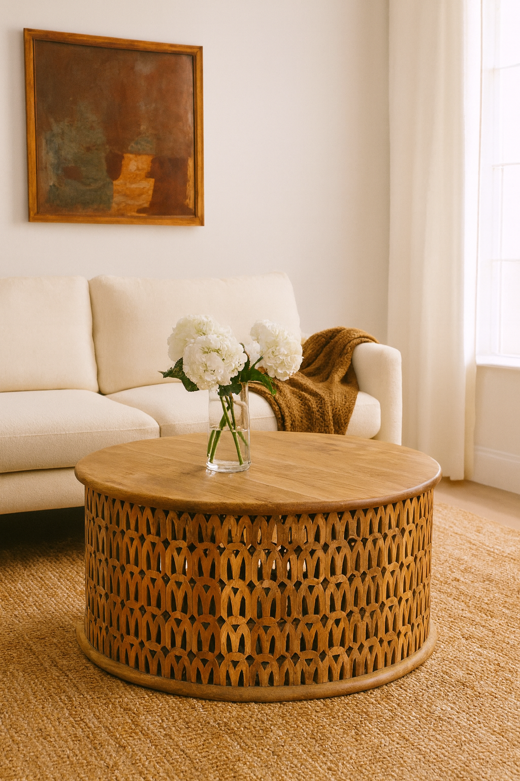 Lifestyle imagination of a round mango wood coffee table with hand-carved lattice base and smooth natural top; carved coffee table mango wood, 90 cm diameter, 45 cm height.