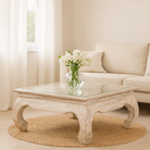 Lifestyle imagination of a of a Indian coffee table made from mango wood with Orissa-style carvings and glass top; mango wood coffee table, 90 × 90 × 30 cm.