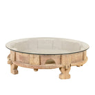 White background image of a round reclaimed teak coffee table with glass top and hand-carved base; rustic vintage design, 84 cm diameter, 28 cm height.