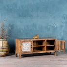 Mango wood low board featuring hand-carved floral motif doors with whitewashed detailing, open central shelving, and a warm natural wood finish.