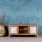 Wooden cabinet with decorative doors against a textured blue wall.
