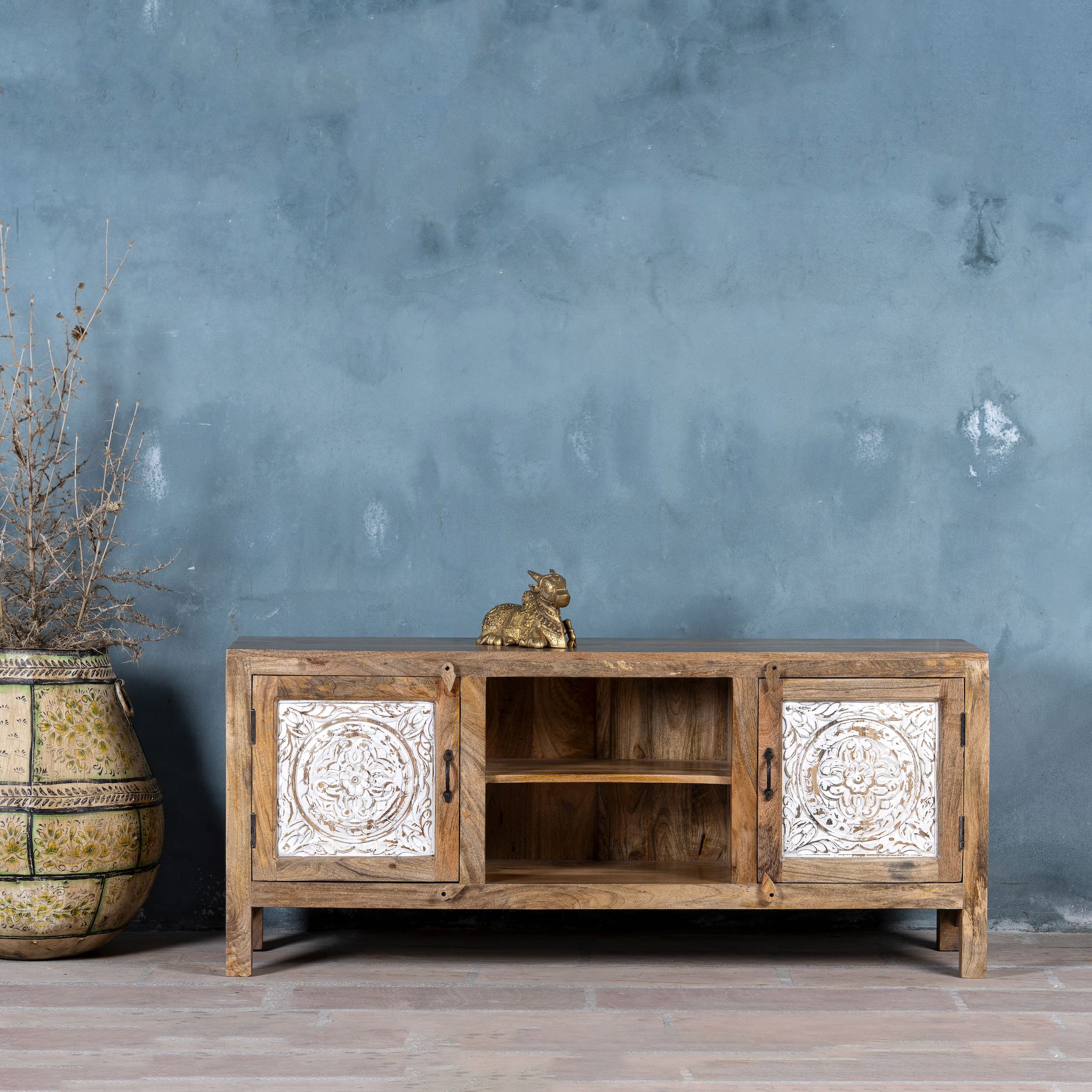 Wooden cabinet with decorative doors against a textured blue wall.
