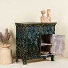 Side angle image with open door of a hand painted cupboard made from recycled wood with floral motifs, two drawers and two doors, 90 × 90 × 40 cm.