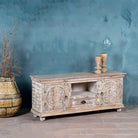 Decorative wooden TV stand against a textured blue wall with two vases on top.