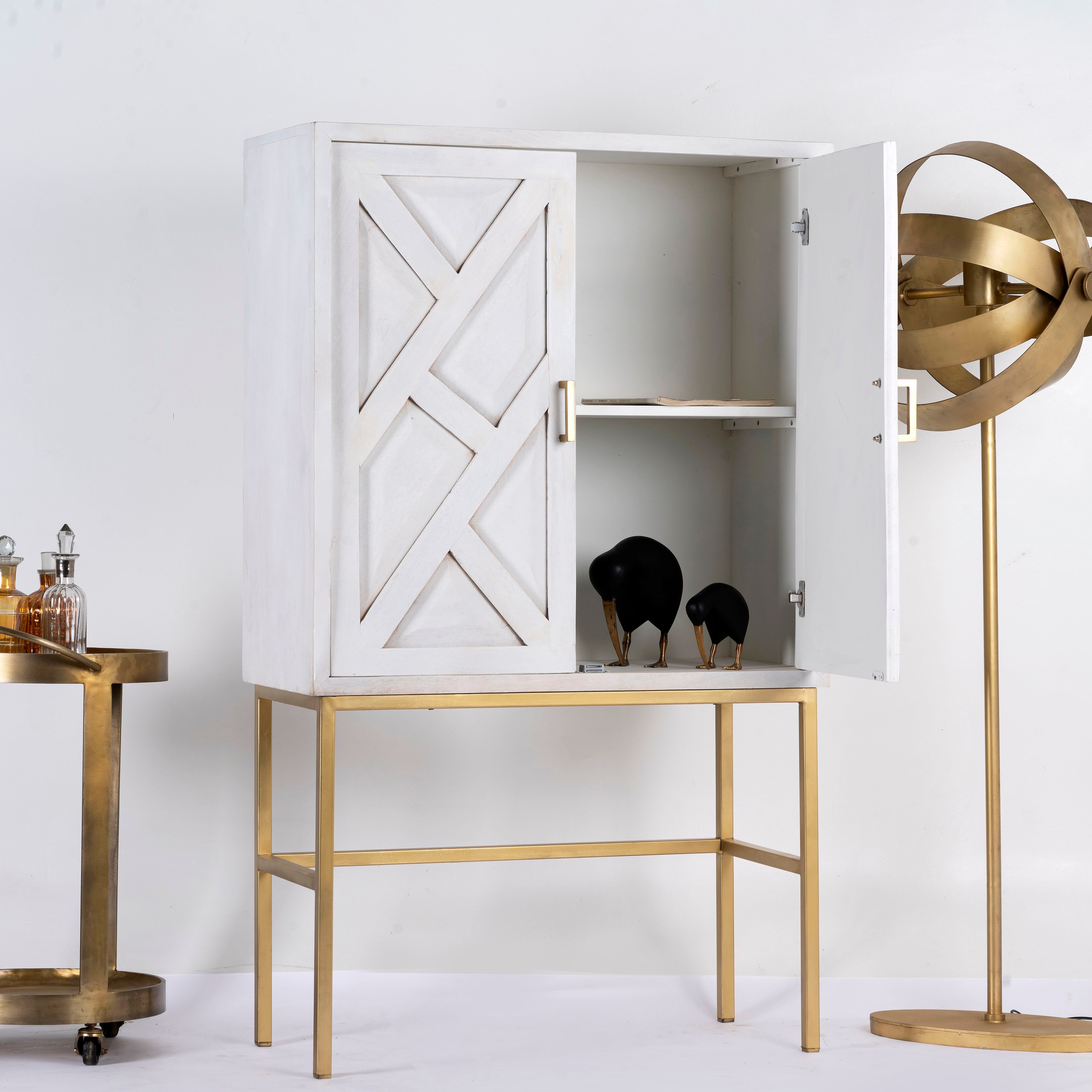 Open door image of a tall whitewashed mango wood cabinet with carved lines and antique brass iron base, 91 × 154 × 43 cm.
