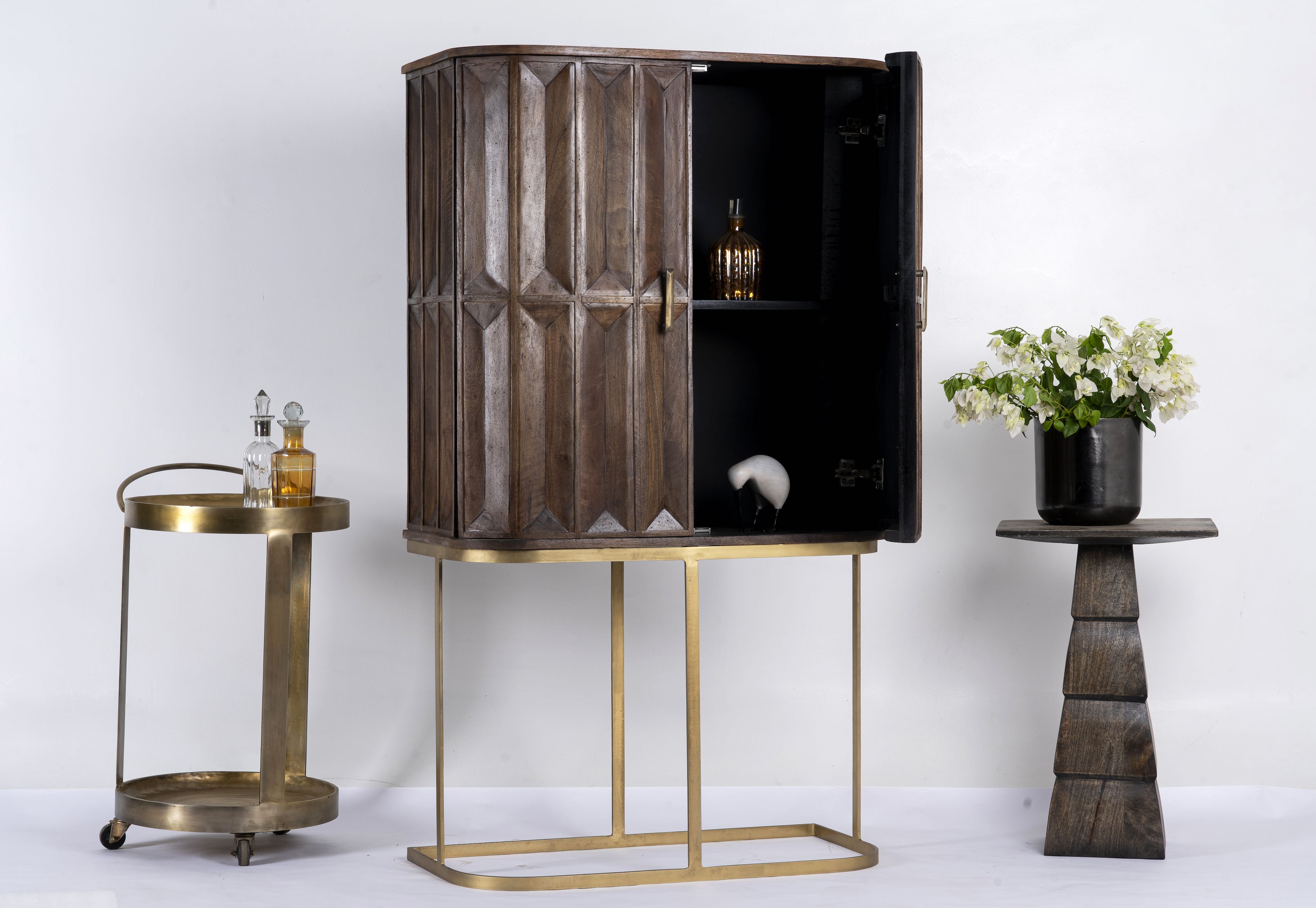 Side angle image with open doors of a tall mango wood cabinet with diamond tile carving, bronze handles, and black metal base, 86 × 42 × 150 cm.
