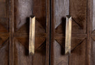 Close up image of a tall mango wood cabinet with diamond tile carving, bronze handles, and black metal base, 86 × 42 × 150 cm.