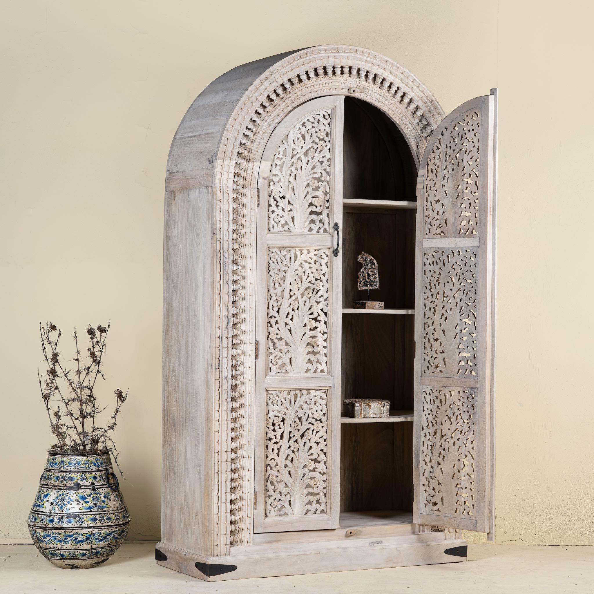 Open door picture of a mango wood cabinet with intricately hand-carved doors and an arched half-round top, showcasing a detailed tree motif and traditional Indian craftsmanship.