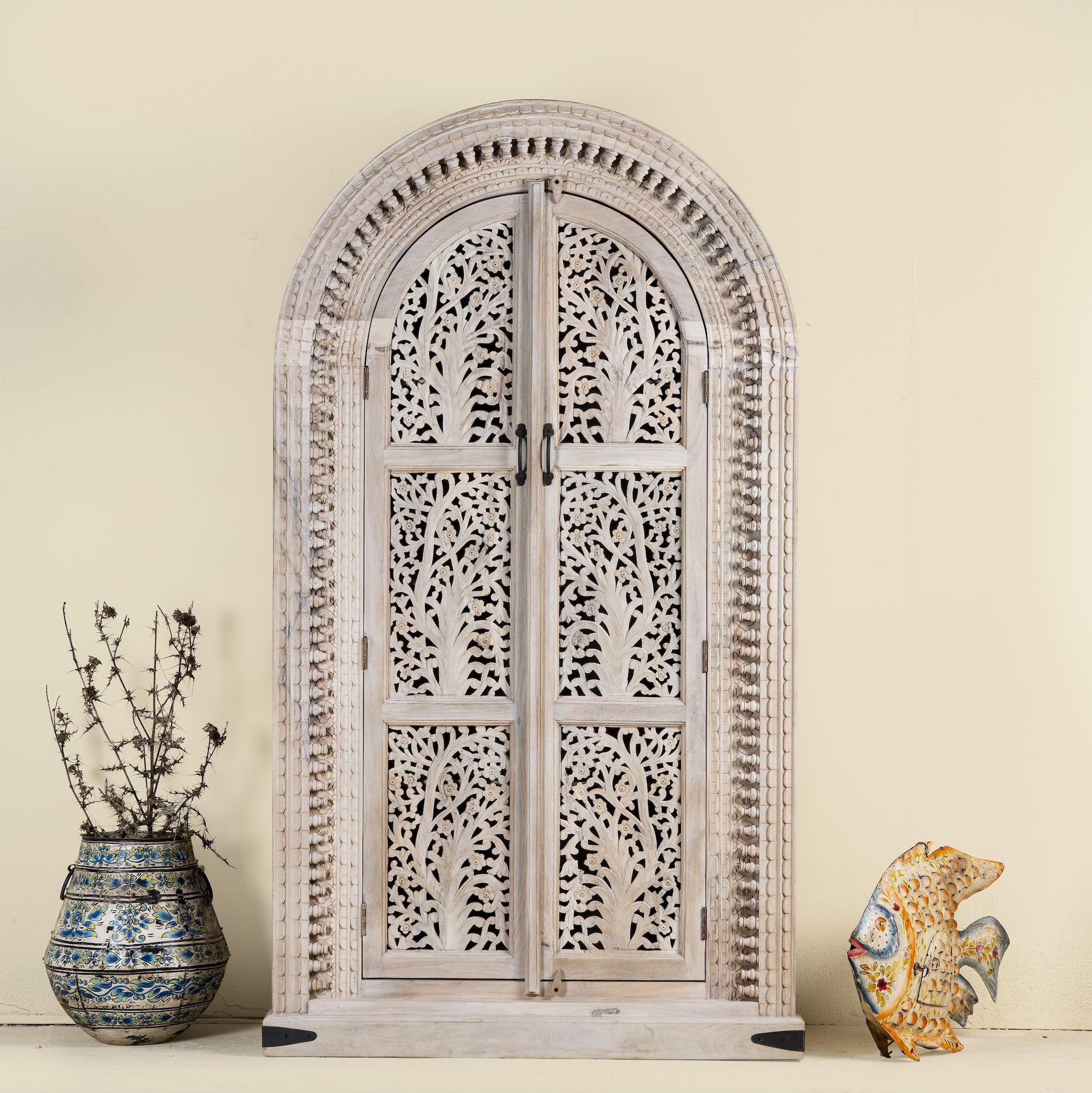 Mango wood cabinet with intricately hand-carved doors and an arched half-round top, showcasing a detailed tree motif and traditional Indian craftsmanship.
