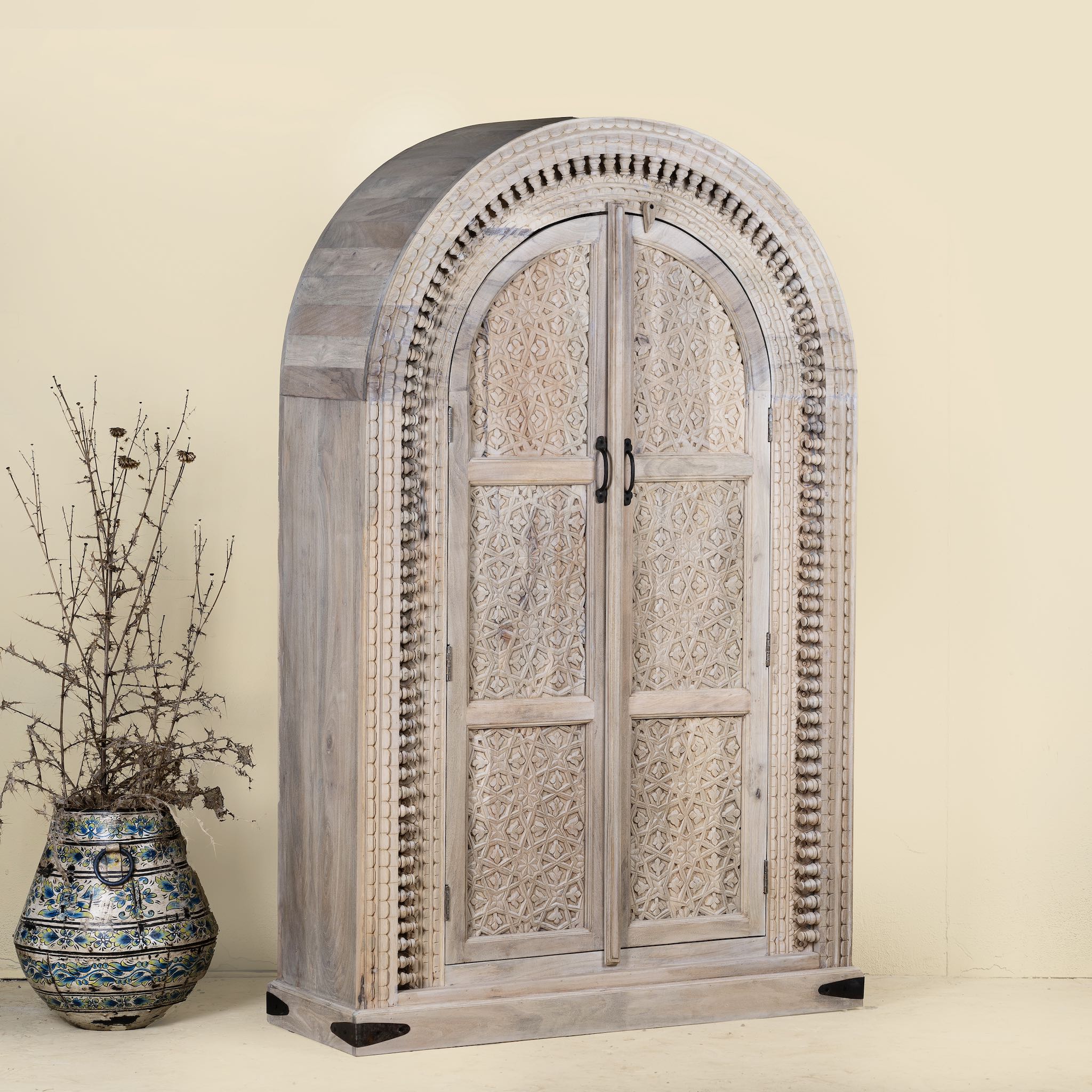 Decorative wooden armoire with intricate carvings on a beige background