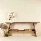 Console table crafted from reclaimed teak wood, featuring a minimalist rustic design with angled legs and a lower shelf, showcasing the natural grain, texture, and character of the weathered wood.
