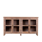 White background image of a rustic showcase cabinet made from recycled teak wood, featuring four glass-paneled doors with brass handles and a lightly weathered finish, offering a warm, natural look ideal for displaying decor or tableware.
 