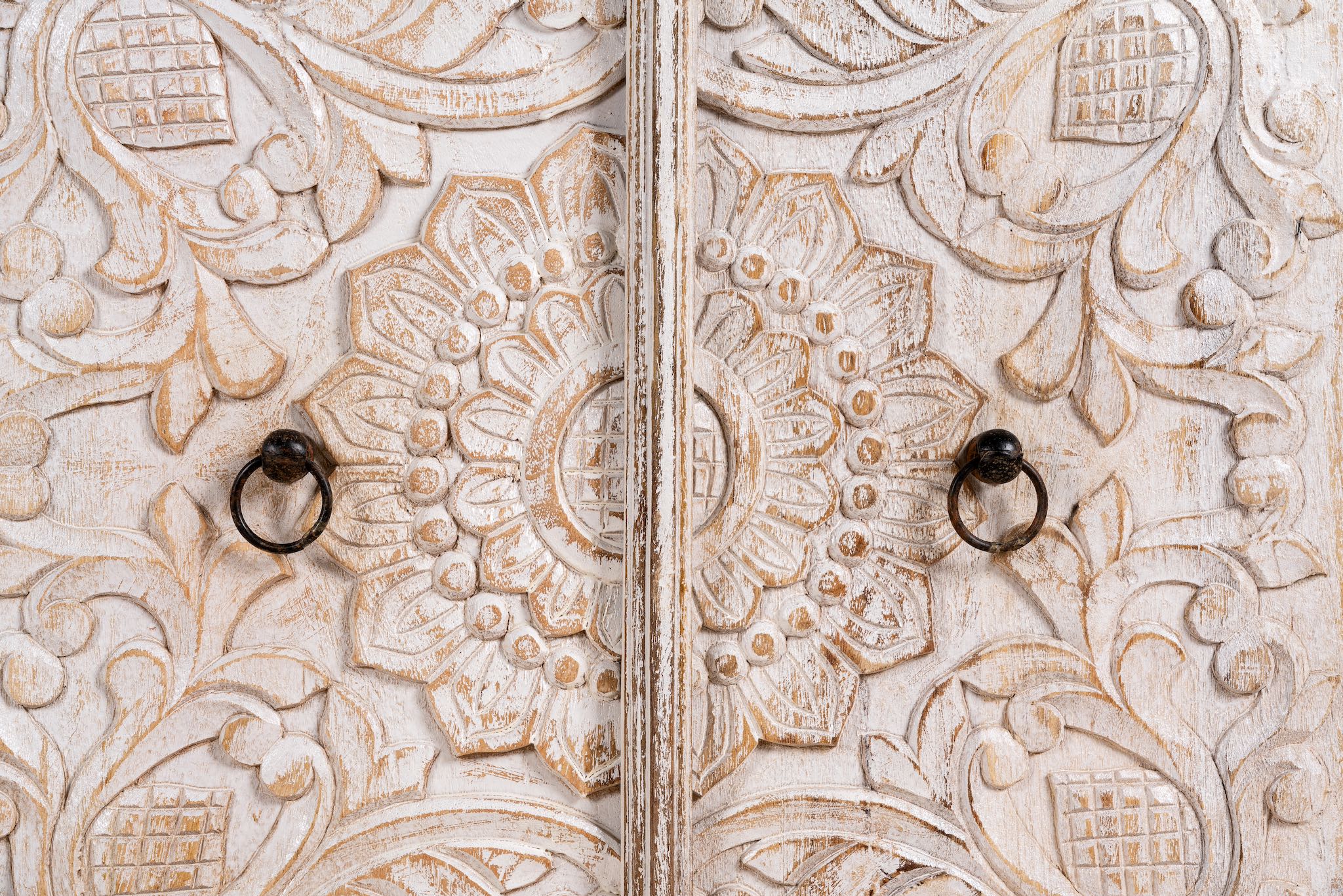Close up image of a hand-carved mango wood Mediterranean lowboard with floral engravings and whitewashed finish – carved wooden furniture combining traditional Indian craftsmanship with rustic elegance.