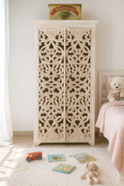 Lifestyle image of a hand-carved mango wood cabinet with floral and geometric motifs in white-washed finish – carved wooden furniture with Mediterranean-inspired design.