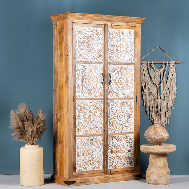 Side angle image of a mango wood wardrobe with whitewashed floral carvings, vintage furniture cabinet in carved wood, 190 × 105 × 42 cm.