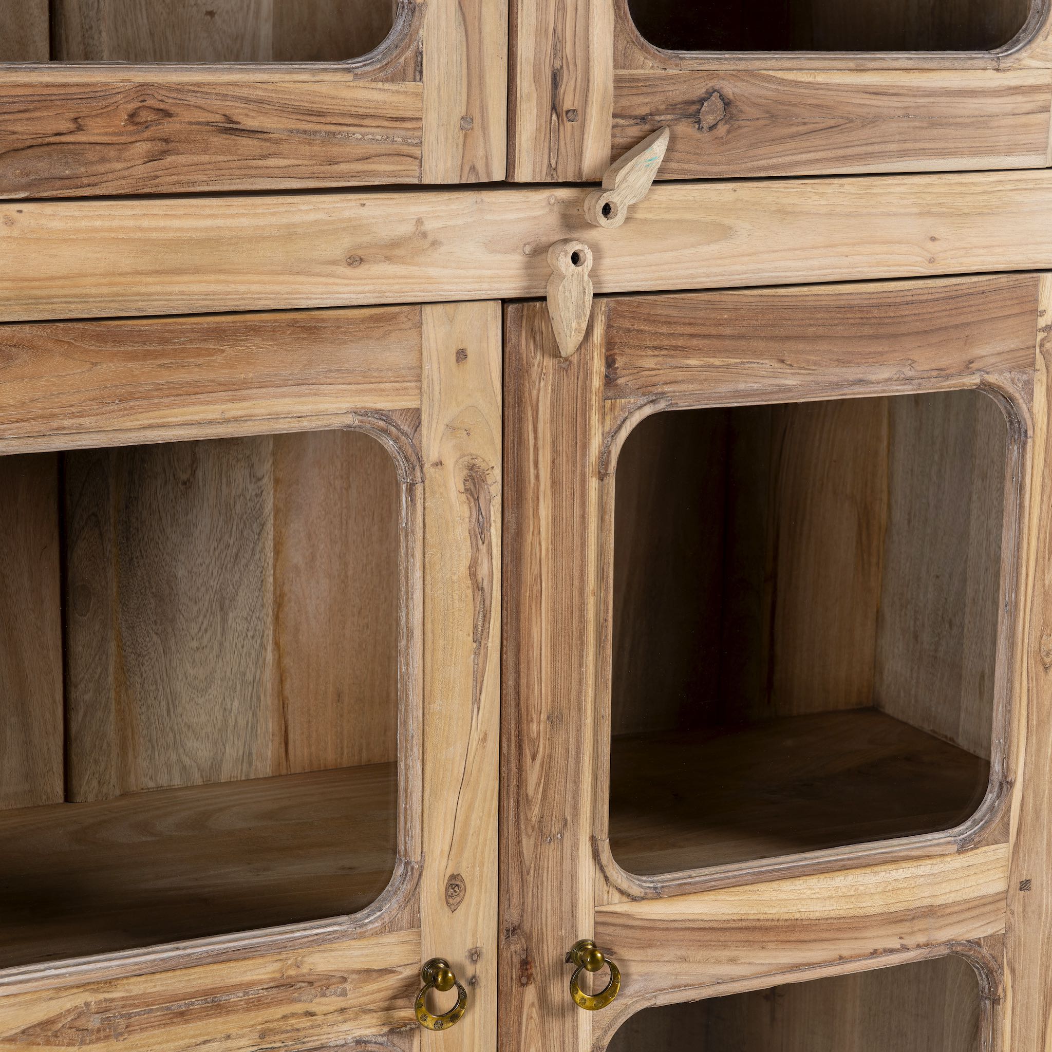 Close up picture of a minimalist display cabinet crafted from reclaimed teak window frames, featuring glass-panelled doors and a natural wood finish for a rustic yet refined look.