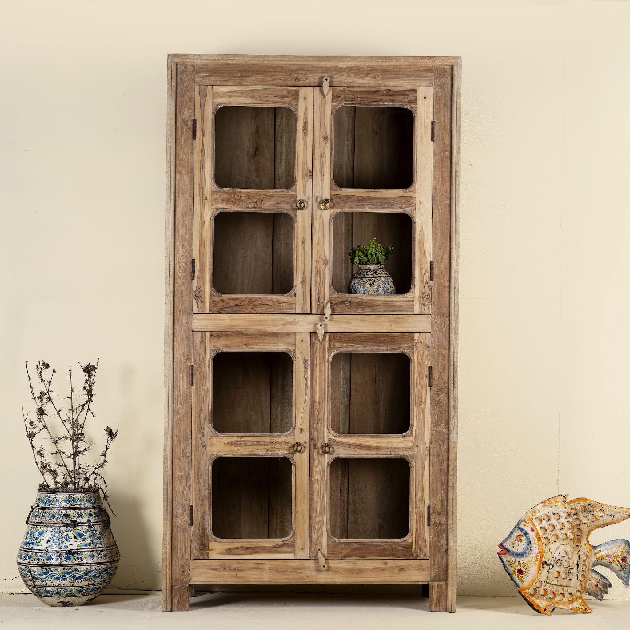 Minimalist display cabinet crafted from reclaimed teak window frames, featuring glass-panelled doors and a natural wood finish for a rustic yet refined look.