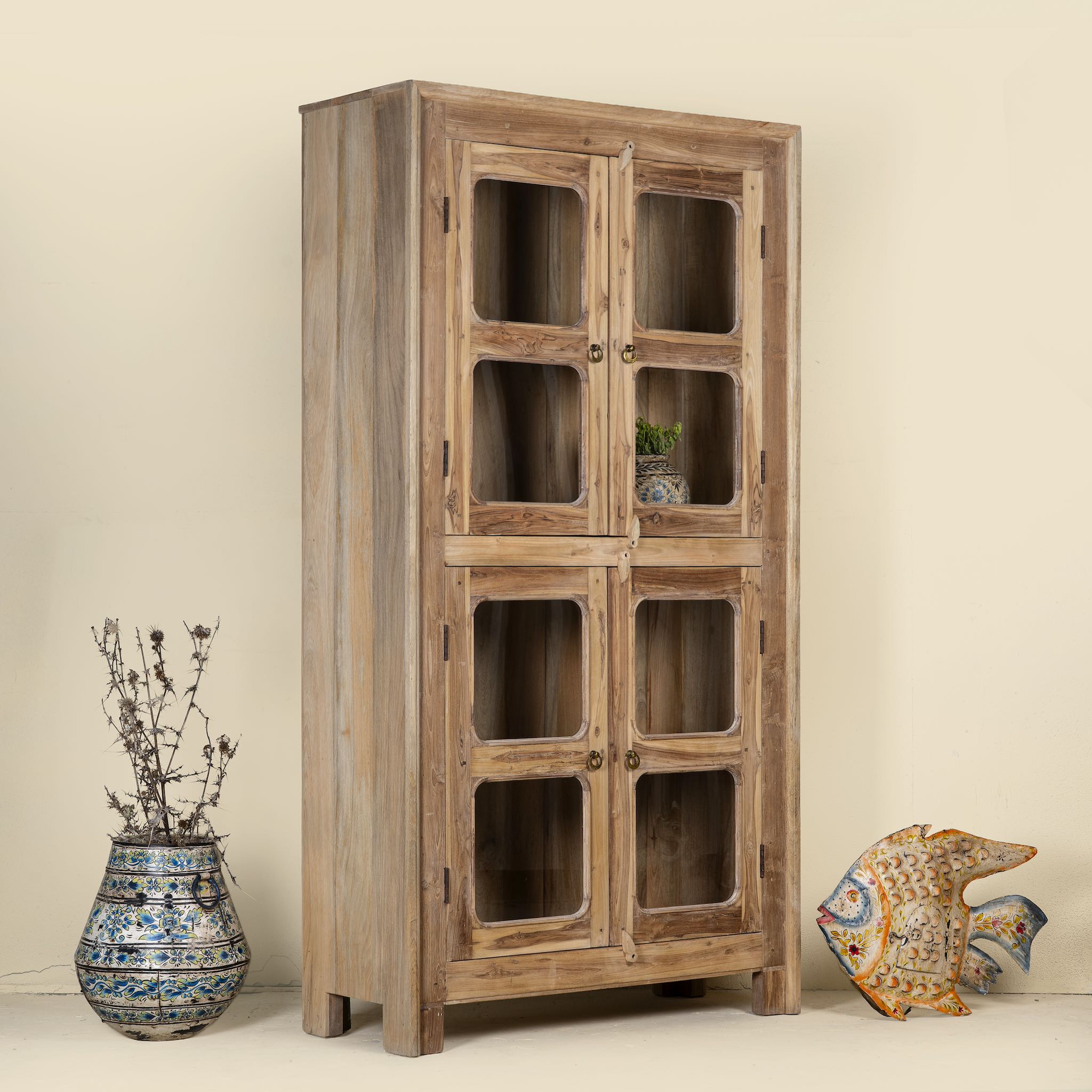 Side angle view of a minimalist display cabinet crafted from reclaimed teak window frames, featuring glass-panelled doors and a natural wood finish for a rustic yet refined look.