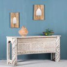 Side angle image of a white-washed carved console table made from reclaimed wood with floral detailing; Mediterranean and Ibiza style furniture, 160 × 80 × 48 cm.