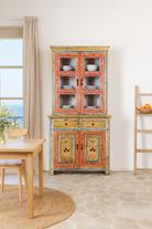 Lifestyle image of a hand-painted two-part showcase made of reclaimed wood with floral motifs; unique furniture for a boho chic living room, 94 × 48 × 203 cm.