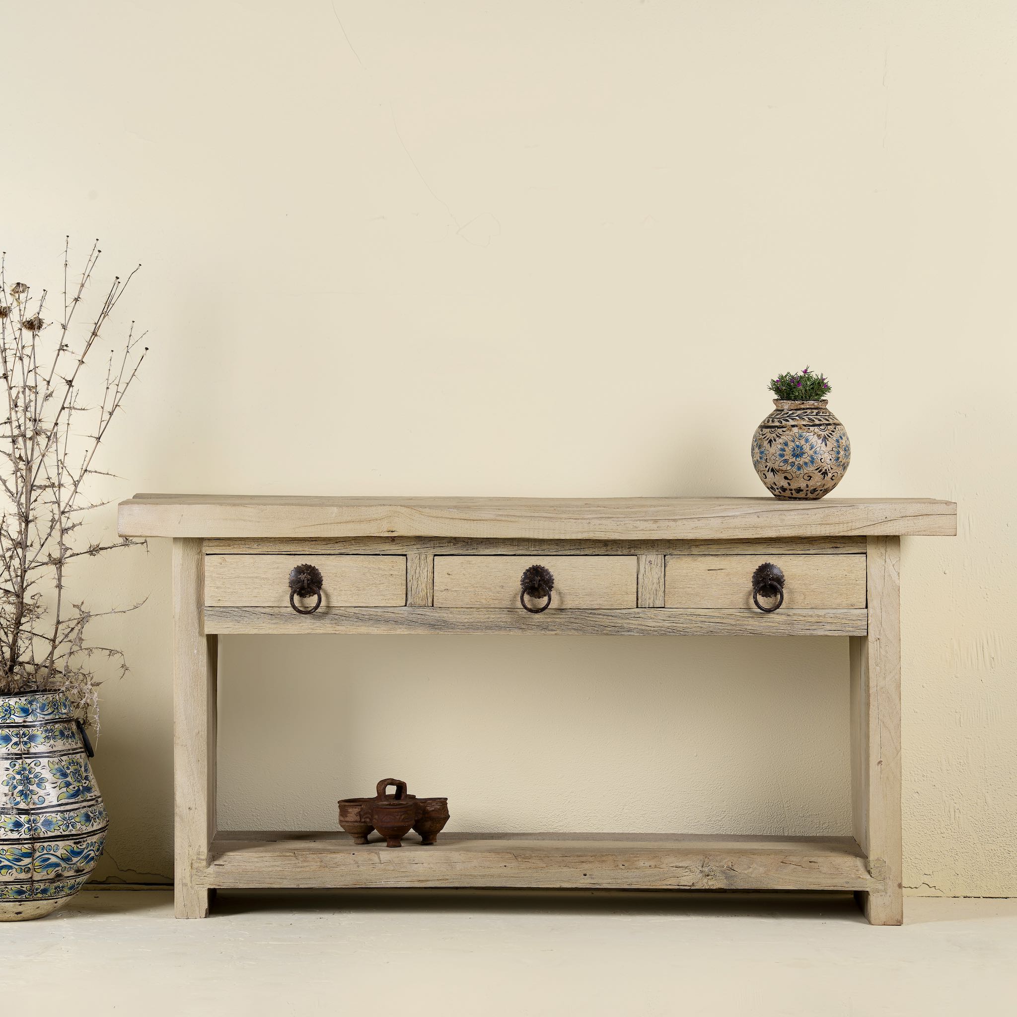 Wooden console table with decorative items against a plain wall