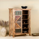 Side angle image with open door of a  handcrafted cabinet made from mango wood, featuring double doors with intricate multicoloured geometric latticework panels, combining natural wood tones with a vibrant, artisanal aesthetic.
