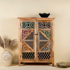 Front view image of a handcrafted cabinet made from mango wood, featuring double doors with intricate multicoloured geometric latticework panels, combining natural wood tones with a vibrant, artisanal aesthetic.
