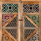 Close up image of a handcrafted cabinet made from mango wood, featuring double doors with intricate multicoloured geometric latticework panels, combining natural wood tones with a vibrant, artisanal aesthetic.
