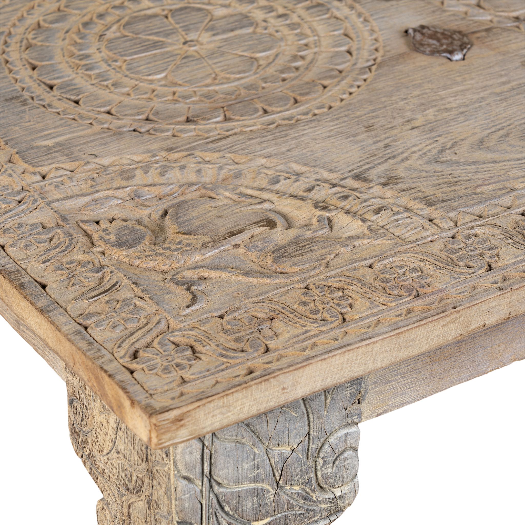Close up image of a sandblasted reclaimed teak wood coffee table with carved antique Indian door top; unique teak wood furniture and living room furniture, 140 × 40 × 48 cm.