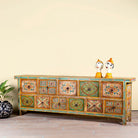 Side angle image of a hand painted mango wood chest of 11 drawers with floral motifs; artisanal mango wood furniture and hand painted furniture, 250 × 41 × 85 cm.
