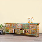 Side angle image with open drawers of a hand painted mango wood chest of 11 drawers with floral motifs; artisanal mango wood furniture and hand painted furniture, 250 × 41 × 85 cm.