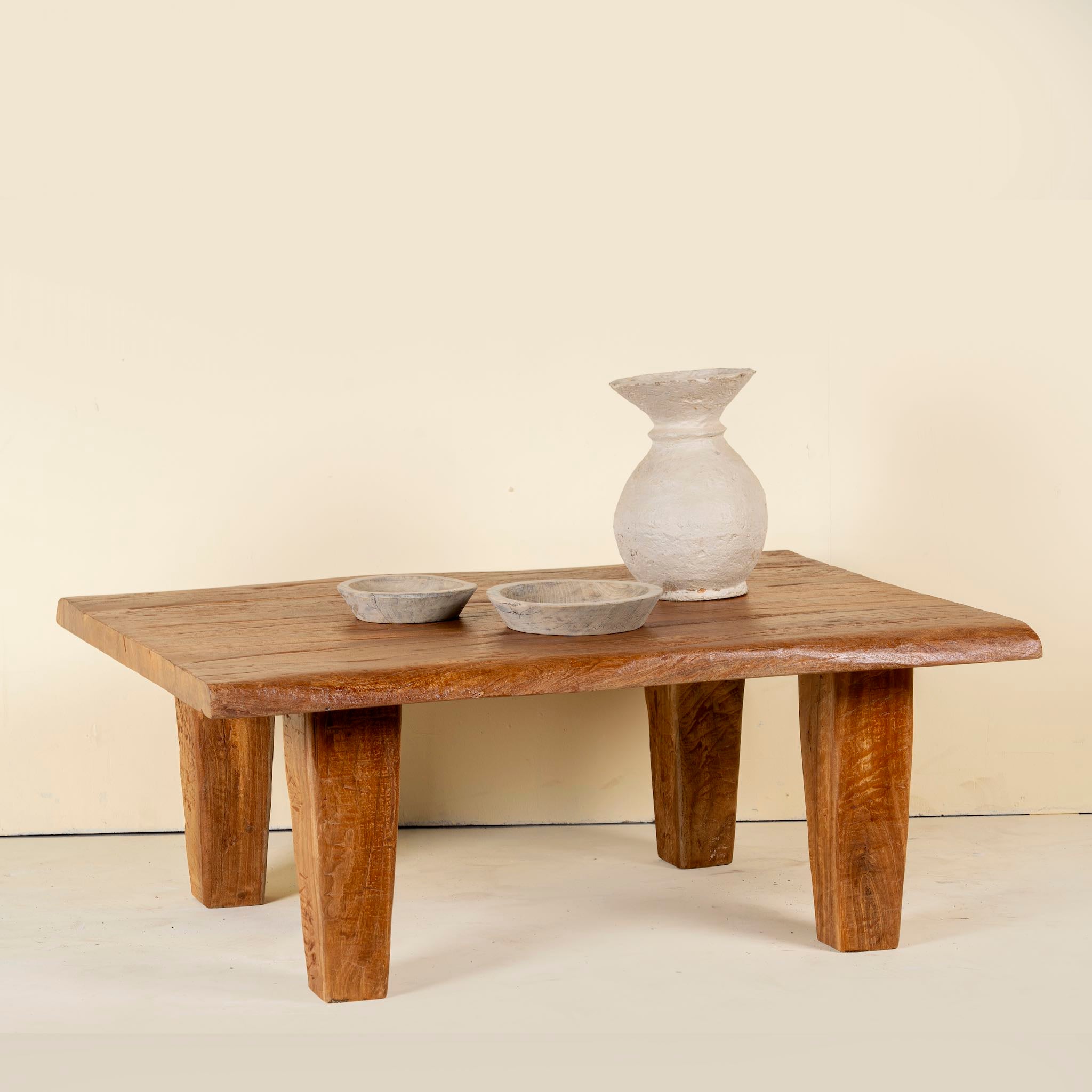 Rectangular rustic coffee table made from reclaimed wood, featuring a thick solid top and tapered legs with a natural, hand-finished look.
