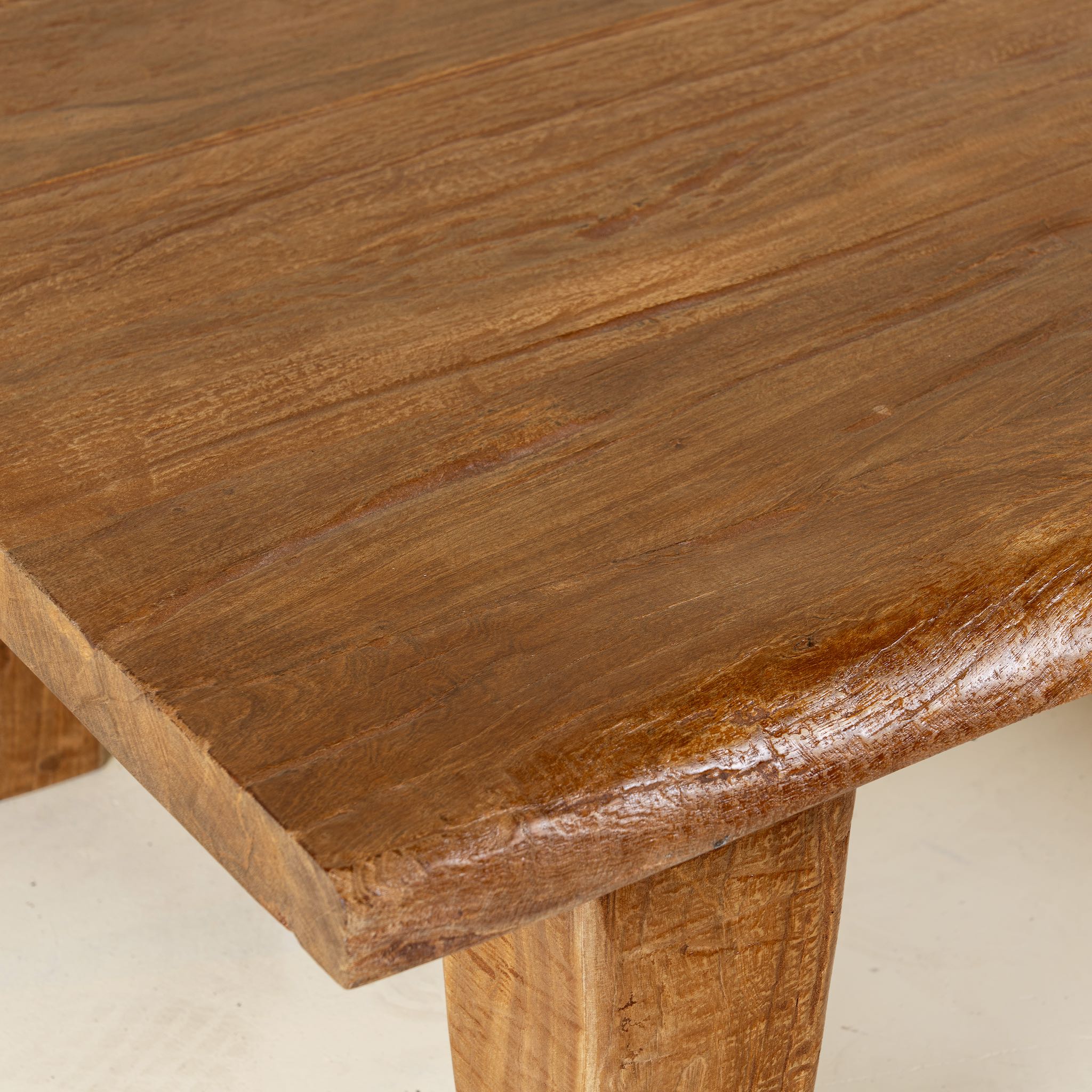 Close up picture of a rectangular rustic coffee table made from reclaimed wood, featuring a thick solid top and tapered legs with a natural, hand-finished look.