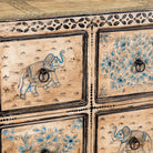 Close up image of a hand painted mango wood chest of 10 drawers with elephant and floral motifs; hand painted furniture for a boho chic living room, 200 × 41 × 85 cm.