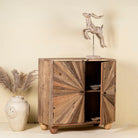 Open door image of a artistic wooden cabinet in rustic style, made from reclaimed wood with a striking sunburst pattern on the double doors, featuring subtle color variations and round metal ring pulls, elevated on rounded wooden feet.
