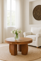 Lifestyle imagination of a rustic wood coffee table with round reclaimed teak top and black charred finish; sustainable furniture, 70 cm diameter, 40 cm height.