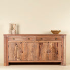 Carved acacia wood sideboard with four doors, two drawers, brass handles, and tapered legs; artisanal acacia wood furniture, 180 × 40 × 90 cm.