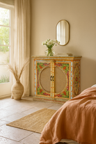 Lifestyle imagination of a hand-painted, hand-carved cupboard made of mango wood with floral design and rattan inserts.