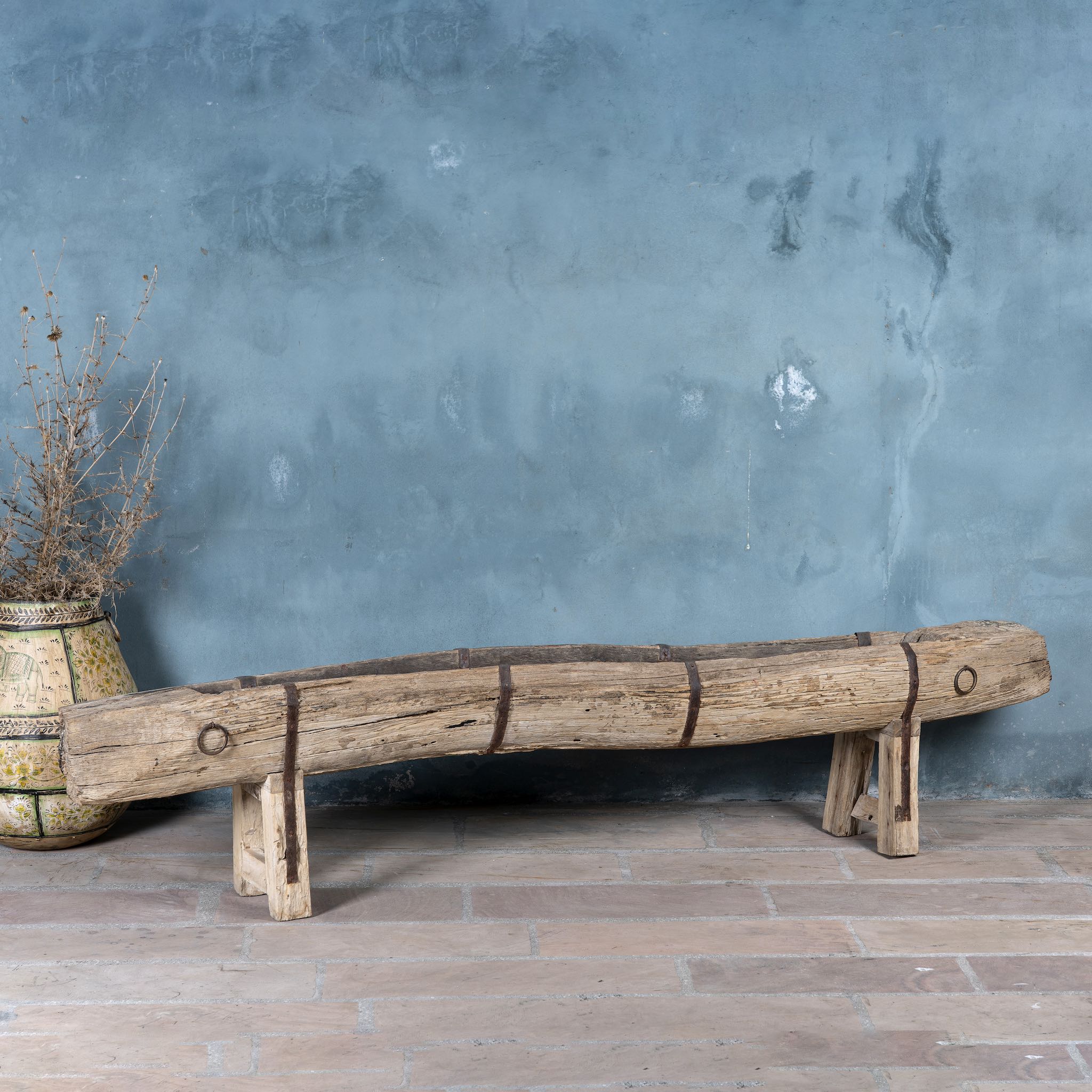 Antique Indian feeding bench made from solid teak wood, featuring original iron fittings and a weathered finish- a rare rustic accent with authentic charm.