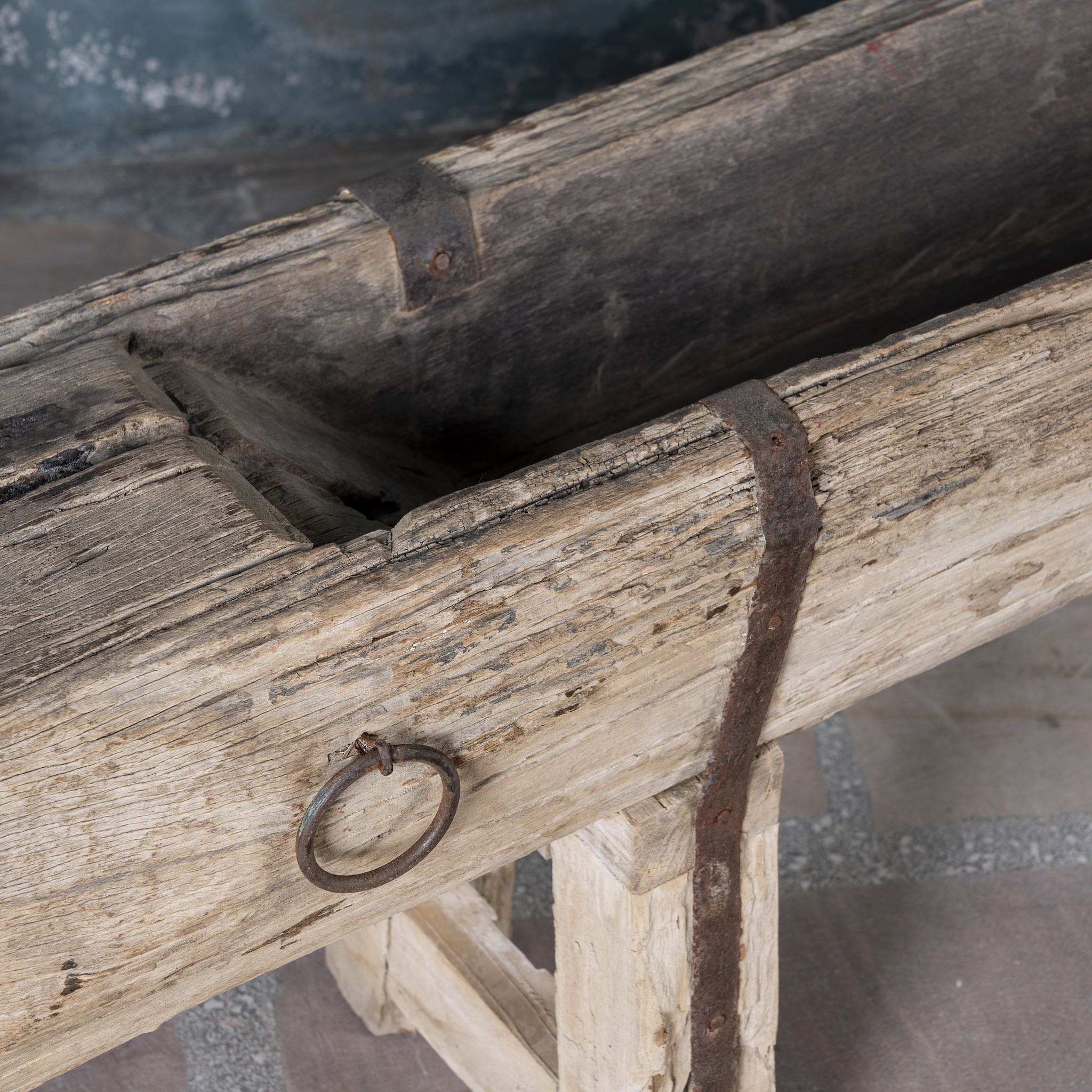 Close up picture of an antique Indian feeding bench made from solid teak wood, featuring original iron fittings and a weathered finish- a rare rustic accent with authentic charm.