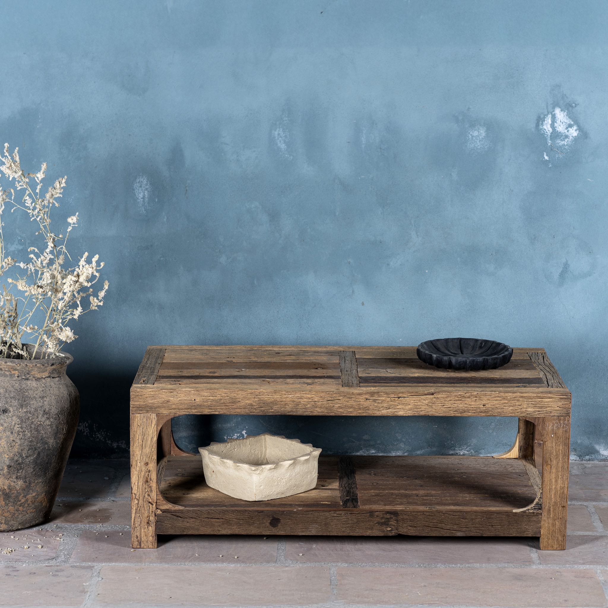 Front view of a coffee table made of reclaimed wood in Wabi Sabi style decorated in a living room scene.